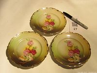 Three plates displayed front showing pattern and gold rims