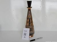 Full view of smoke glass decanter with stopper and gold trim next to pen for scale