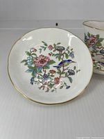 Top view of saucer showing bird & floral pattern and gold rim; cup partially visible