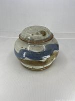 Front view of lidded stoneware jar showing glaze colors and form