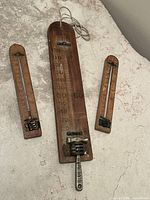 Three wooden wall thermometers laid out together