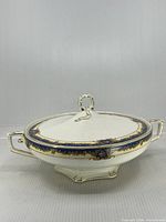 Side view of covered tureen showing handles, foot and border design