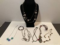 All jewelry pieces displayed together including bust with silver-tone disc necklace and six additional pieces laid out