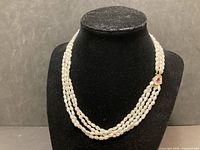 Full view of three-strand baroque pearl necklace on display bust