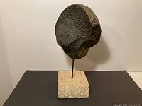 full view of abstract metal sculpture on stone base