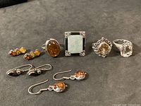 Group shot of four rings and three earring pairs on black background