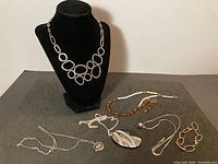 Group shot of all seven jewelry pieces displayed, showing variety of necklaces, bracelet and earrings