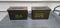 Front view of both ammunition cans showing yellow stencil and red lid edge
