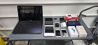 All items laid out on cart: laptop, tablets, phones, console, boxes, cables
