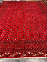 Full view of red Turkmen rug showing borders and fringe