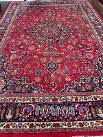 Full view of entire rug showing red field, borders and overall condition