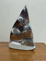 Front view of polished aluminum sailboat sculpture