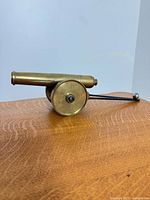 Right side view of brass cannon showing barrel, wheel, trailing rod