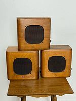 Front view of three stacked wooden RCA speakers showing grille and logo
