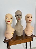 Front view of all three mannequin heads on small table
