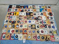 Overhead view of full assortment of ~80 7-inch singles laid out on quilt