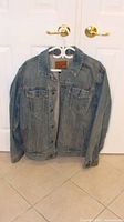 Front view of GAP denim jacket on hanger showing button front and chest pockets