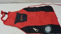 Full view of red and black GMC BBQ apron showing drink pocket, bottle opener, and straps