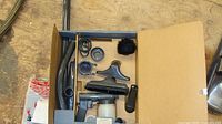 Kirby accessory box opened showing hose, wand, nozzles, spray bottle, adapters