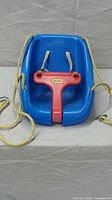 Front view of Little Tikes blue toddler swing showing seat, red T-bar, yellow ropes, safety straps