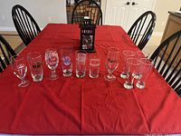 Row of 11 assorted branded beer glasses on table