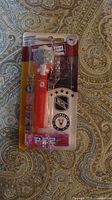 Front of sealed Detroit Red Wings NHL PEZ dispenser showing red stem, goalie mask head, and included candy rolls