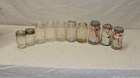 Front view of ten assorted glass preserving jars showing presence or absence of lids