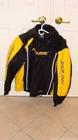 Front view of black and yellow Promax floater jacket on hanger