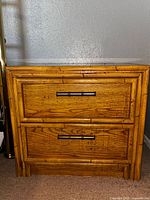 Front view of nightstand showing faux bamboo frame and two drawers