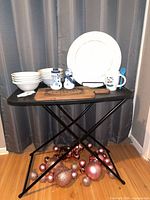 All items displayed on small table: bowls, charger, snowman shakers, cutting board, mug with spoon, pink ornaments