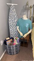 Mannequin, ironing board, basket with contents visible