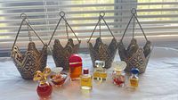 Group shot of four metal crown tealight holders behind seven miniature perfume bottles