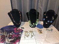All jewellery pieces, scarf, hair clip and three display busts arranged on table
