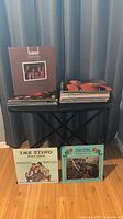Two stacks of vinyl LPs on folding stand; Bread, The Sting, Seals & Crofts visible