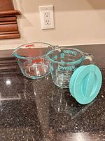 2-cup Pyrex measuring cup with teal lid alongside 4-cup Pyrex cup