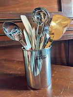 Bain-marie holding assorted stainless, wooden and silicone utensils