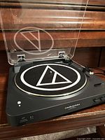 Turntable with dust cover open showing slip mat, tonearm and controls