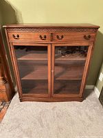 Front view of wood bookcase showing drawers, glass doors, shelves