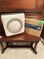 Front view of Coway air purifier next to boxed fresh starter filter