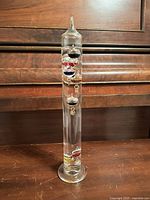 Full view of glass Galileo thermometer showing overall form