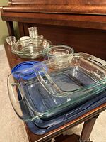 All items stacked on piano: casseroles with lids, pie dishes, mixing bowls, small Duralex and Libbey bowls