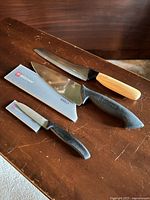 Three knives laid out with two grey sheaths visible