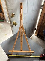 Front view of wooden tripod easel with measuring tape for scale