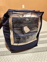 Topper folded inside navy storage case with clear front showing brand insert