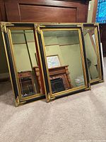 Three matching gilded mirrors leaning against wall