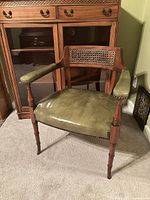 Full view of wooden chair with green leather seat, cane backrest and arm pads