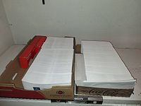 Two flats with large stacks of white #10 envelopes and red self-seal boxes
