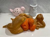 Group shot of owl vase, pink bird, and sunbather figure