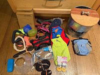 All items laid out including bowls boxes, treat bin, harnesses, toys, coat, leashes, collar, socks, brushes, cone, clicker