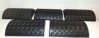 Five identical black plastic footrests with diamond tread pattern displayed side by side